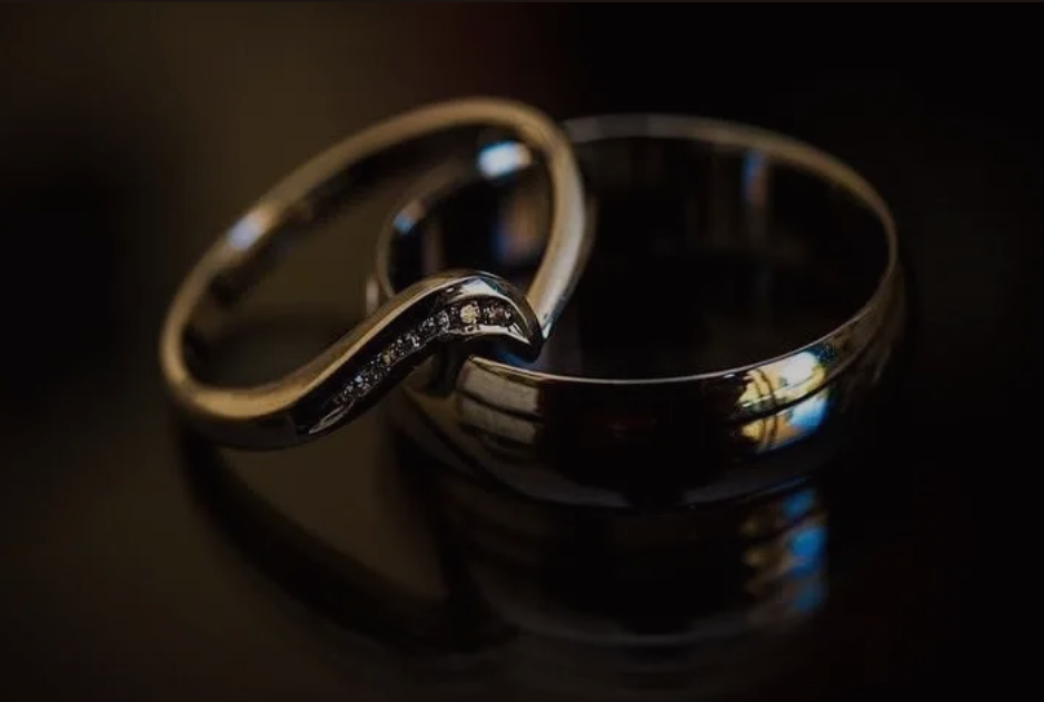 Wedding rings resting on an open book, photographed in soft natural light.